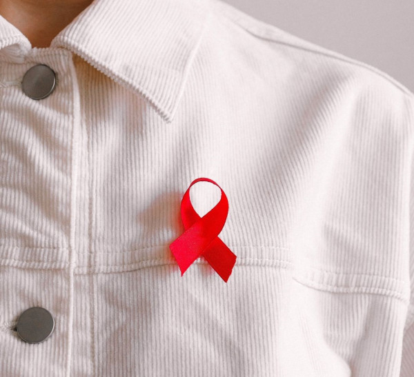A red ribbon for HIV awareness on a white jacket